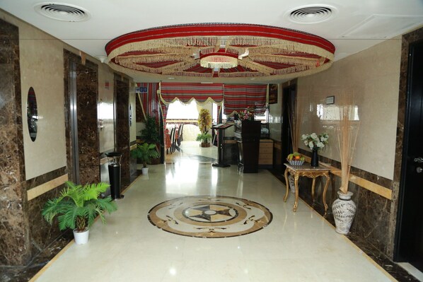 A hotel lobby with a marble floor, a central decorative circular pattern, and a ceiling with a red and beige striped design. - Sharjah Palace Hotel (Sharjah)