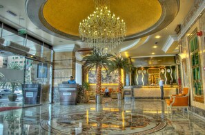 A hotel lobby with a grand chandelier, palm trees, and a reception desk. - Sharjah Palace Hotel (Sharjah)