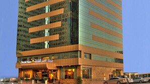 A tall, modern hotel with a prominent sign at the top. - Sharjah Palace Hotel (Sharjah)