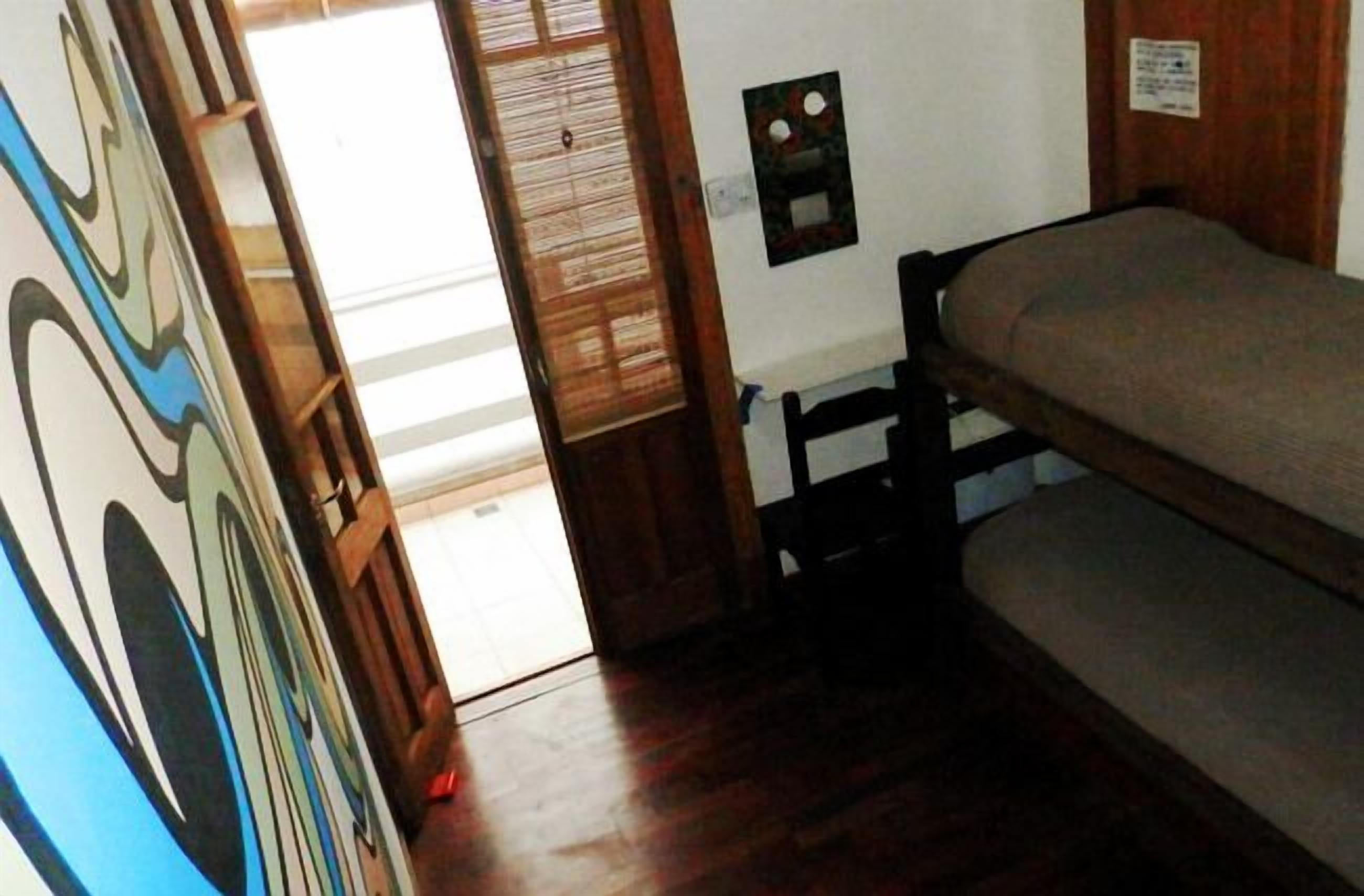 Una habitación con literas, una puerta de madera y un pequeño aire acondicionado de pared.