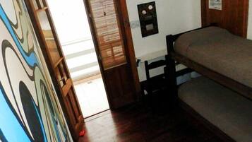 Una habitación con literas, una puerta de madera y un pequeño aire acondicionado de pared.