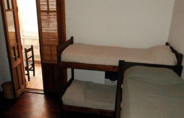 A room with two bunk beds, a wooden door, and a chair. - Llanura Hostel (Rosario)