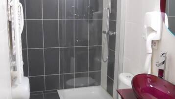 Un baño moderno con ducha acristalada, inodoro blanco y lavamanos rojo.