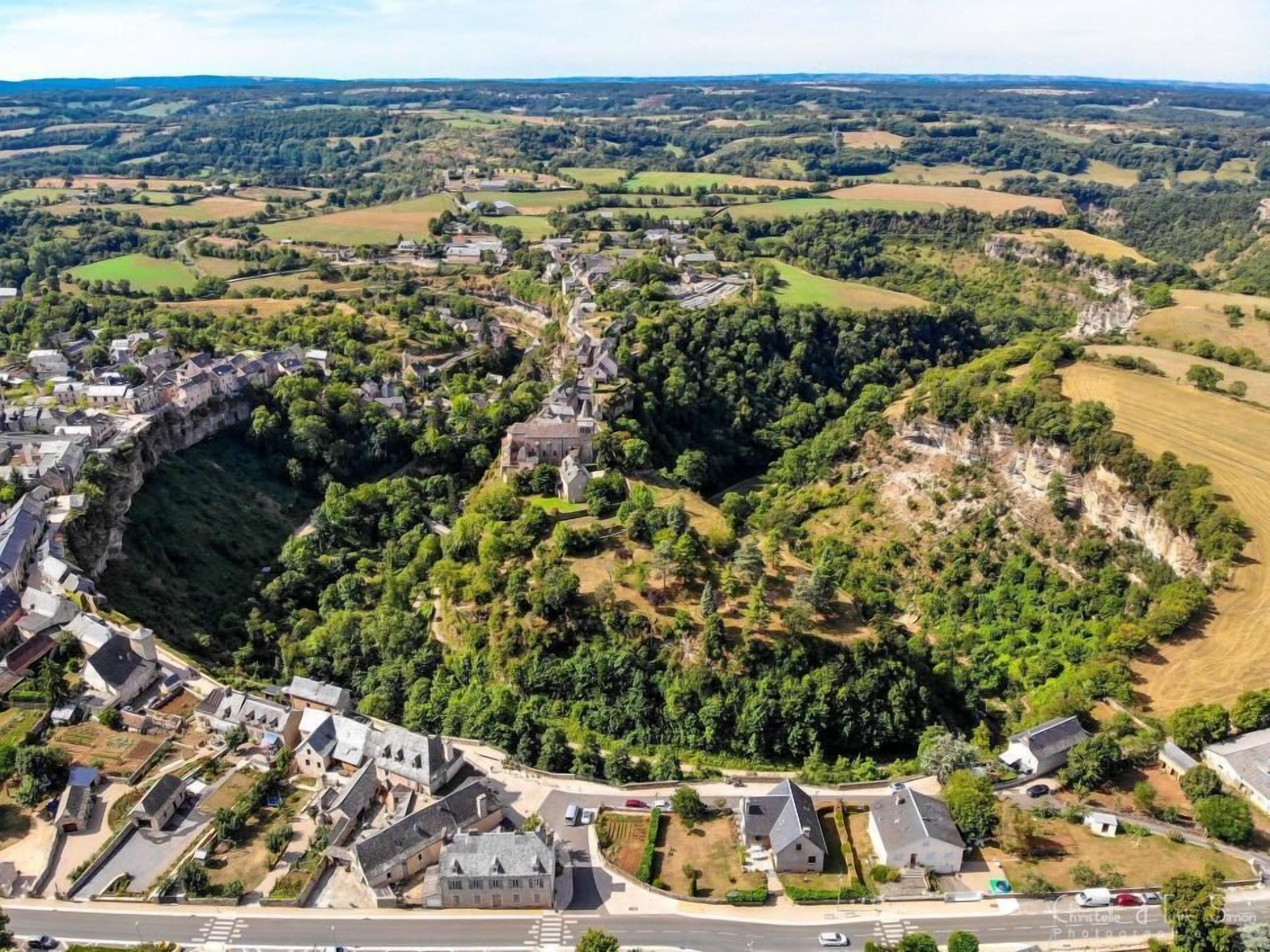 Vue aérienne d’un village avec une falaise imposante et une structure ressemblant à un château.