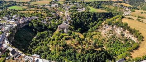 Vue aérienne d’un village avec une falaise imposante et une structure ressemblant à un château.