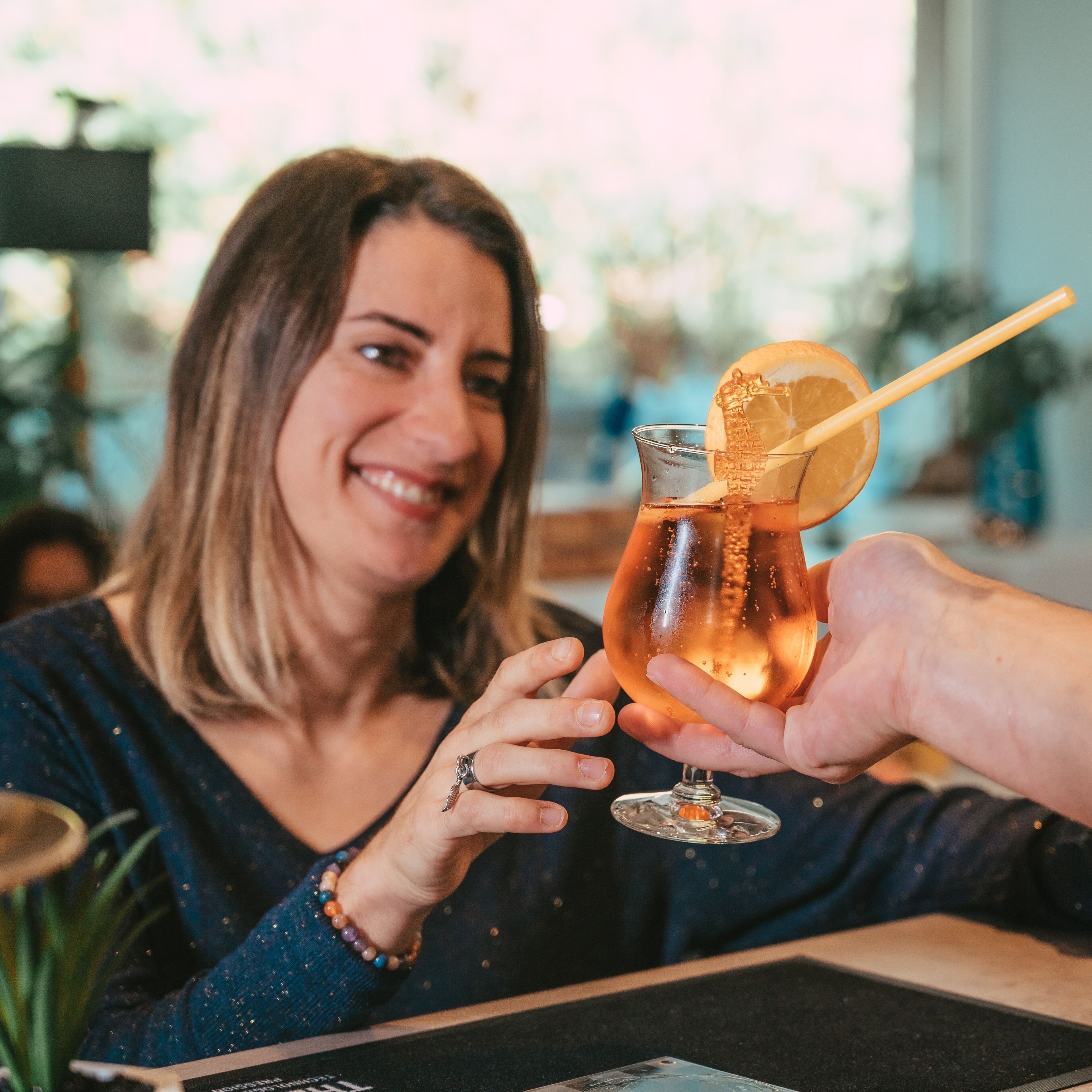 A person holding a glass with a lemon slice and a straw.