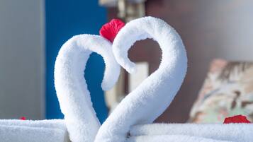 A bed with neatly folded white towels arranged in a heart shape.