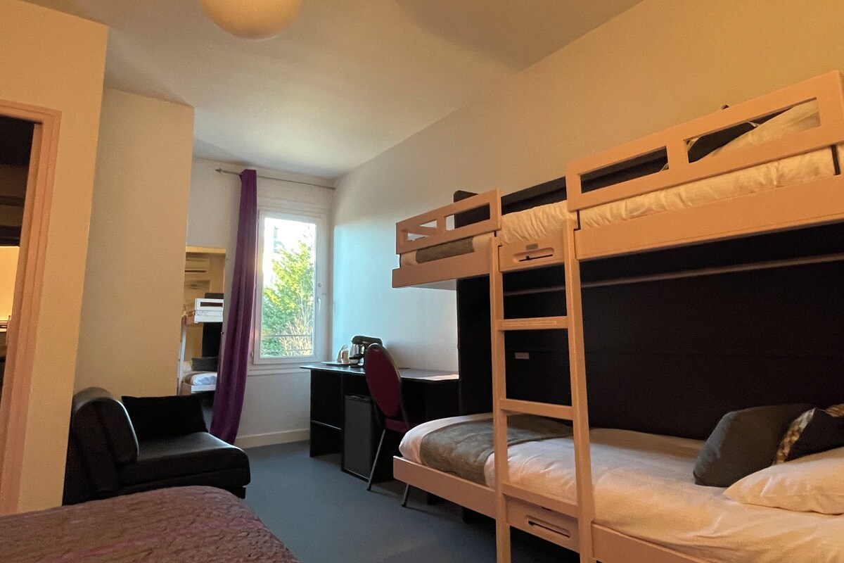 Une chambre avec des lits superposés, un bureau, une chaise et une fenêtre avec des rideaux.