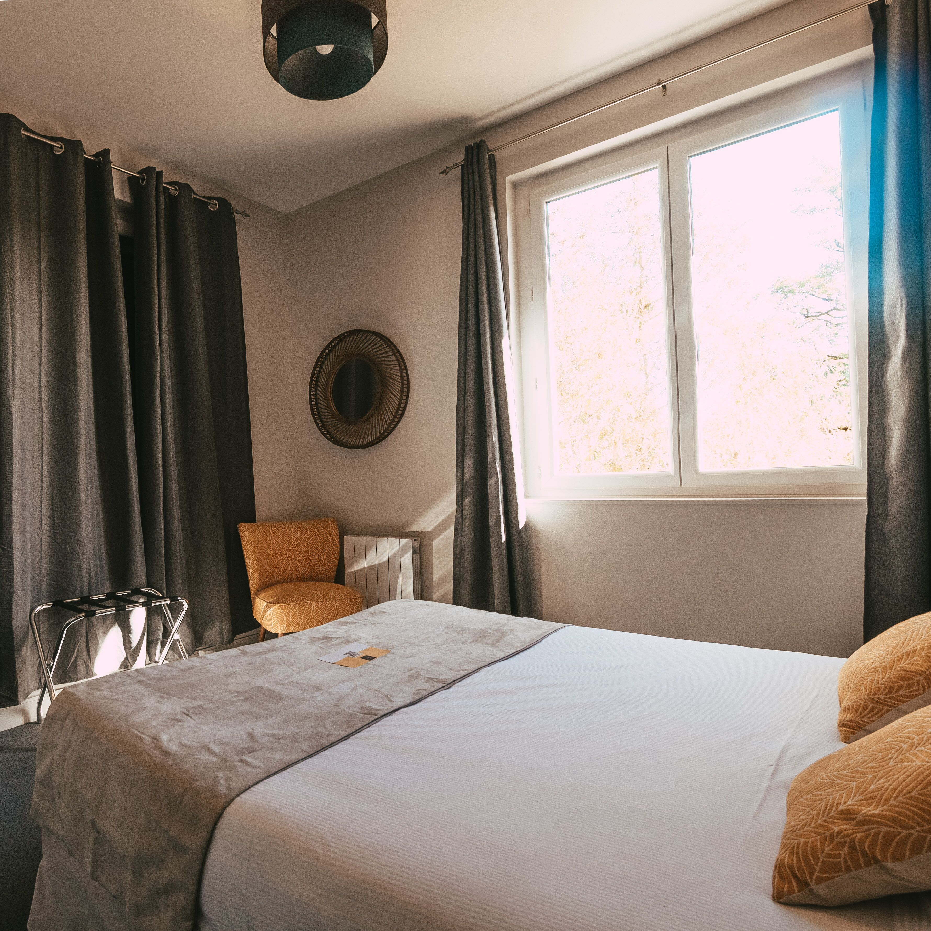 Un dormitorio con cama, una silla, un radiador y una ventana con cortinas.