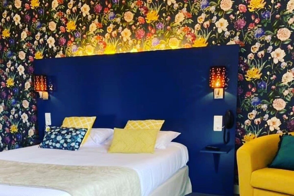 Une chambre à coucher avec un lit, des oreillers, une table de chevet, une lampe et une chaise.
