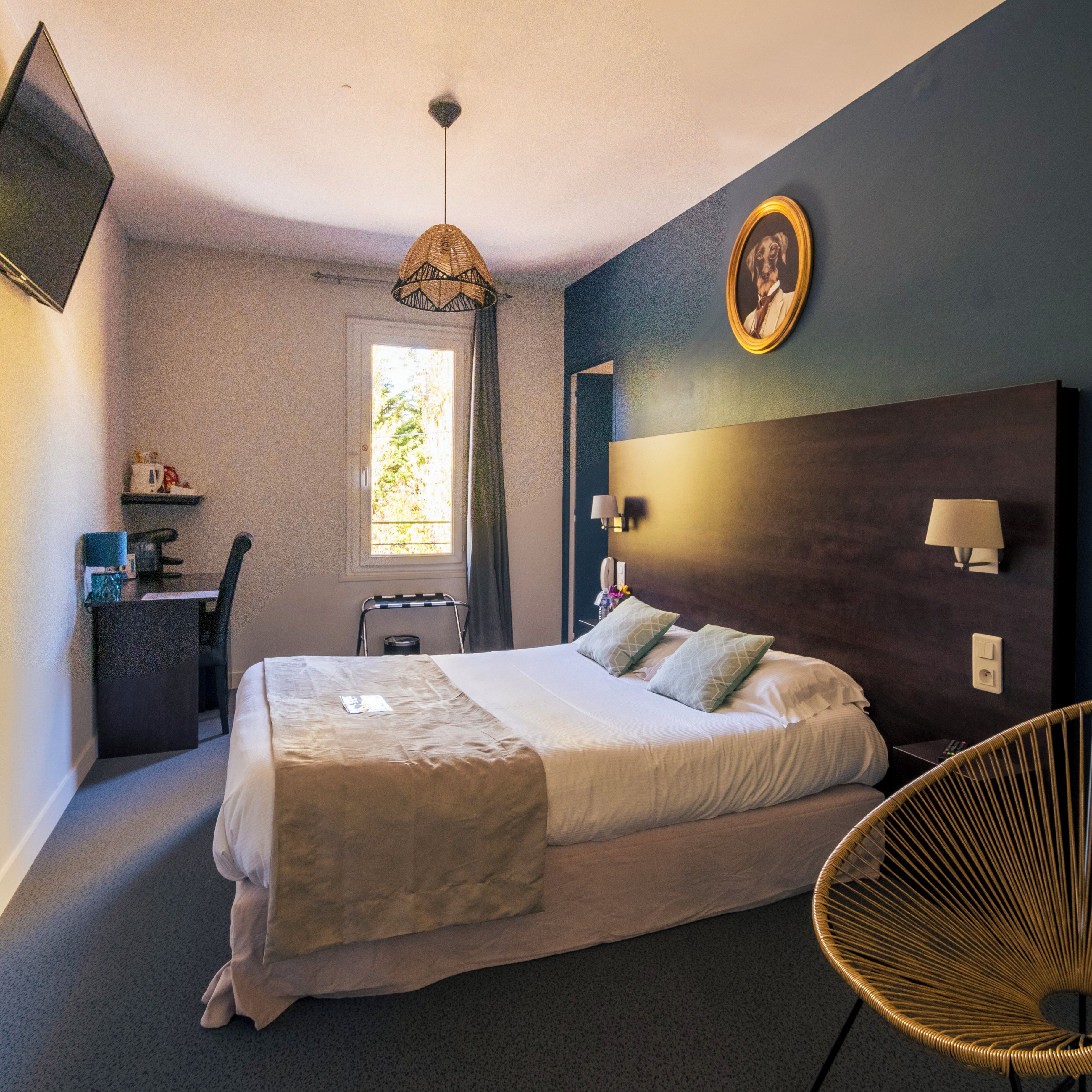 Une chambre à coucher comprenant un lit, des lampes de chevet, un bureau, une chaise, une fenêtre et un tableau accroché au mur.