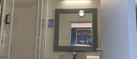 A modern bathroom with a glass shower enclosure, a vanity with a mirror, and a towel rack.