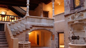 A stone staircase leading to an upper level, a wrought iron gate, and a stone fountain.