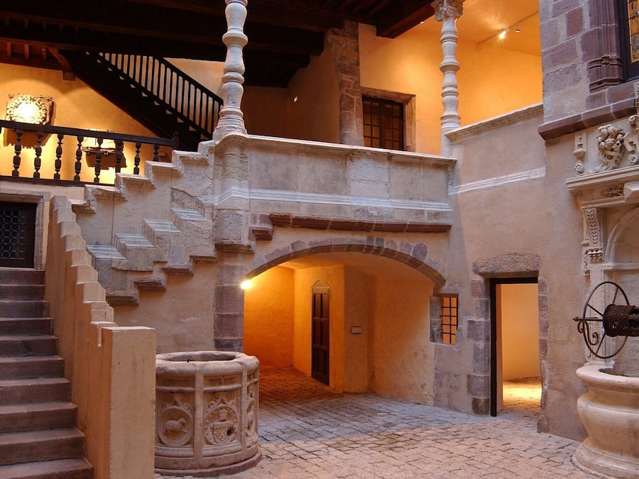 A stone staircase leading to an upper level, a wrought iron gate, and a stone fountain.