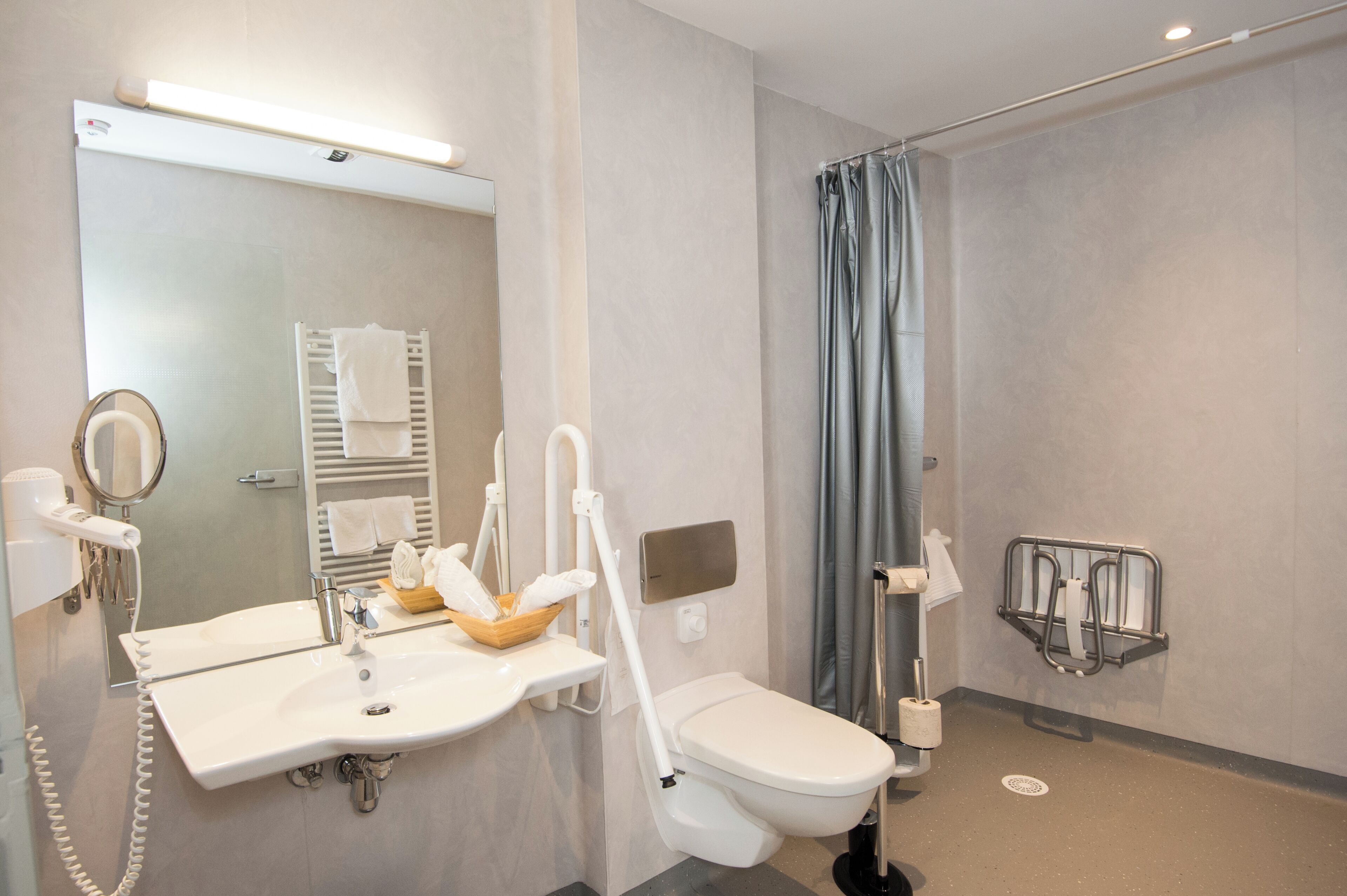 A modern bathroom with a sink, mirror, towel rack, shower curtain, and toilet.