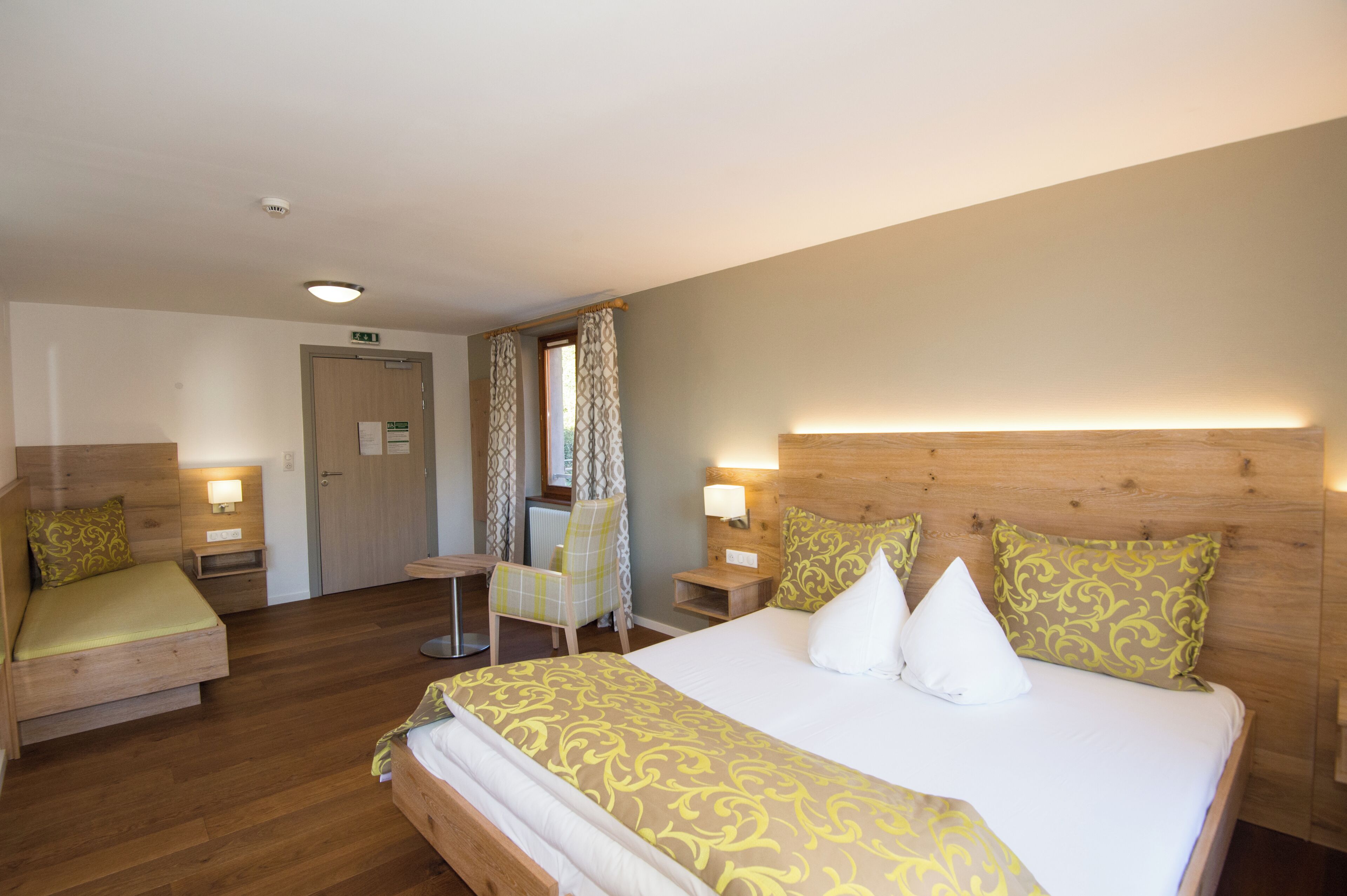 Een hotelkamer met een groot bed, twee nachtkastjes, een stoel en een tafeltje.