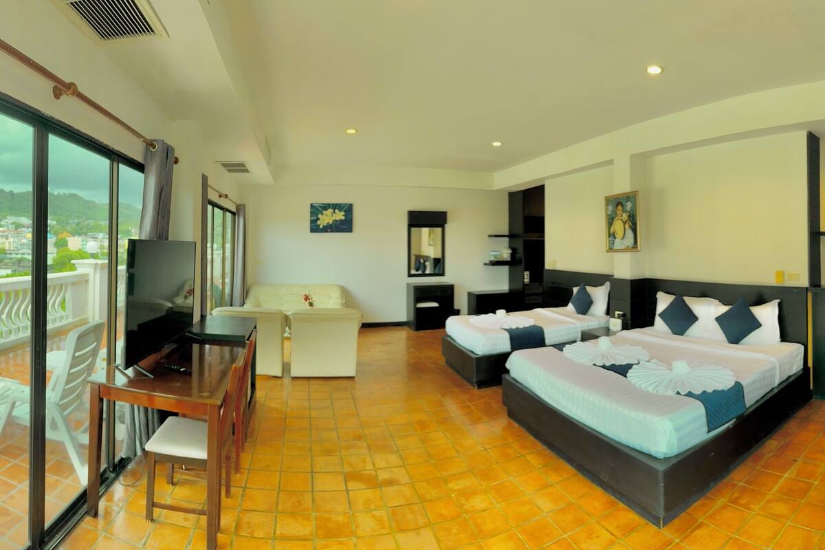 A hotel room with a balcony, a TV, a desk, and two beds.