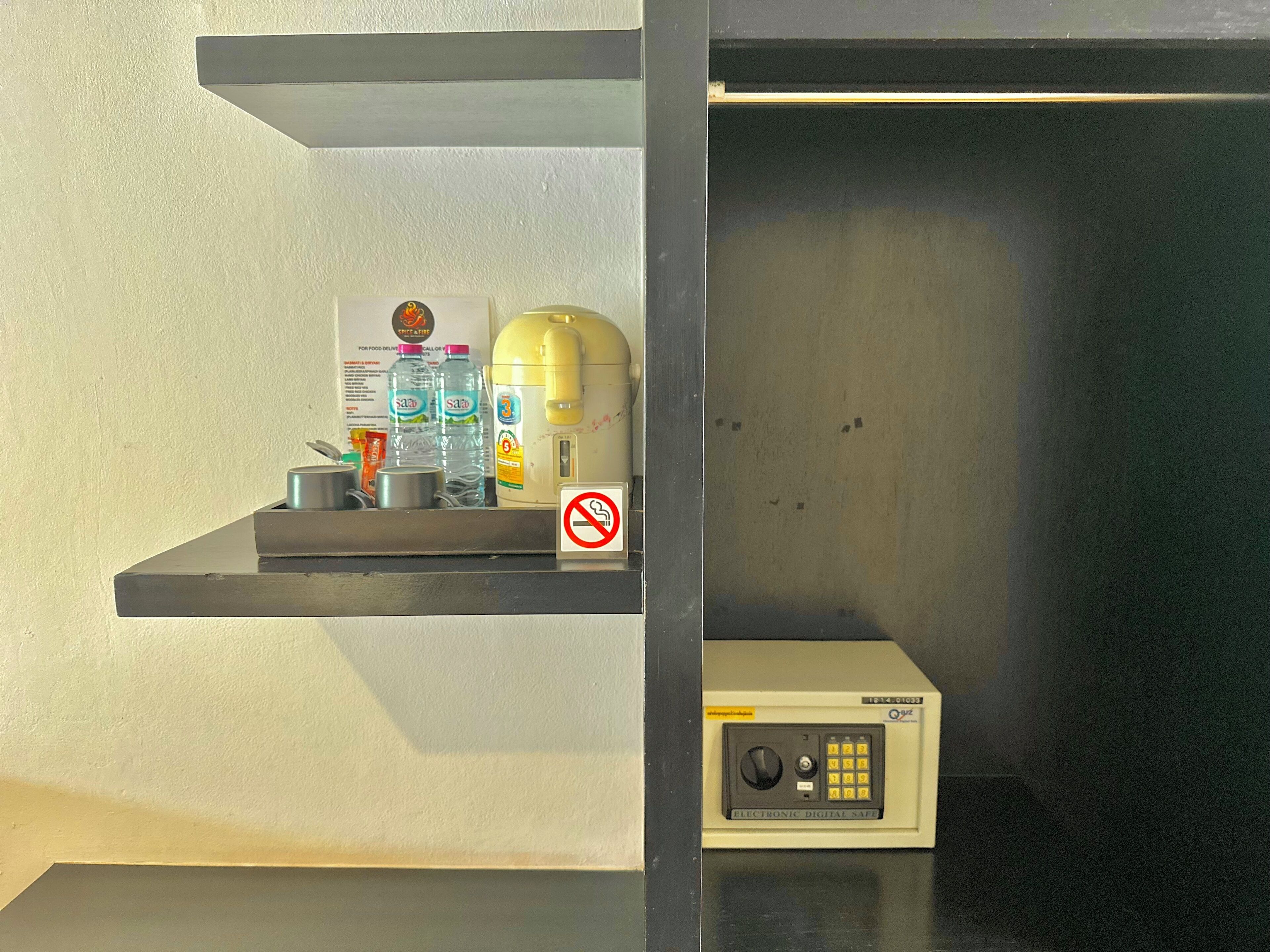Un coin cuisine équipé d’une machine à café, de bouteilles d’eau et d’un panneau indiquant qu’il est interdit de fumer.
