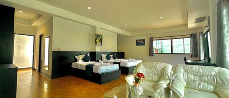 Una habitación de hotel con cama, sofá, una mesita de cristal y ventana con cortinas.