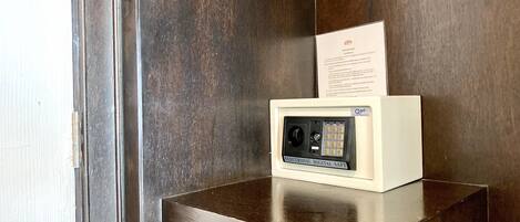 A digital safe with a keypad and a card slot, placed on a wooden cabinet against a dark wooden wall.