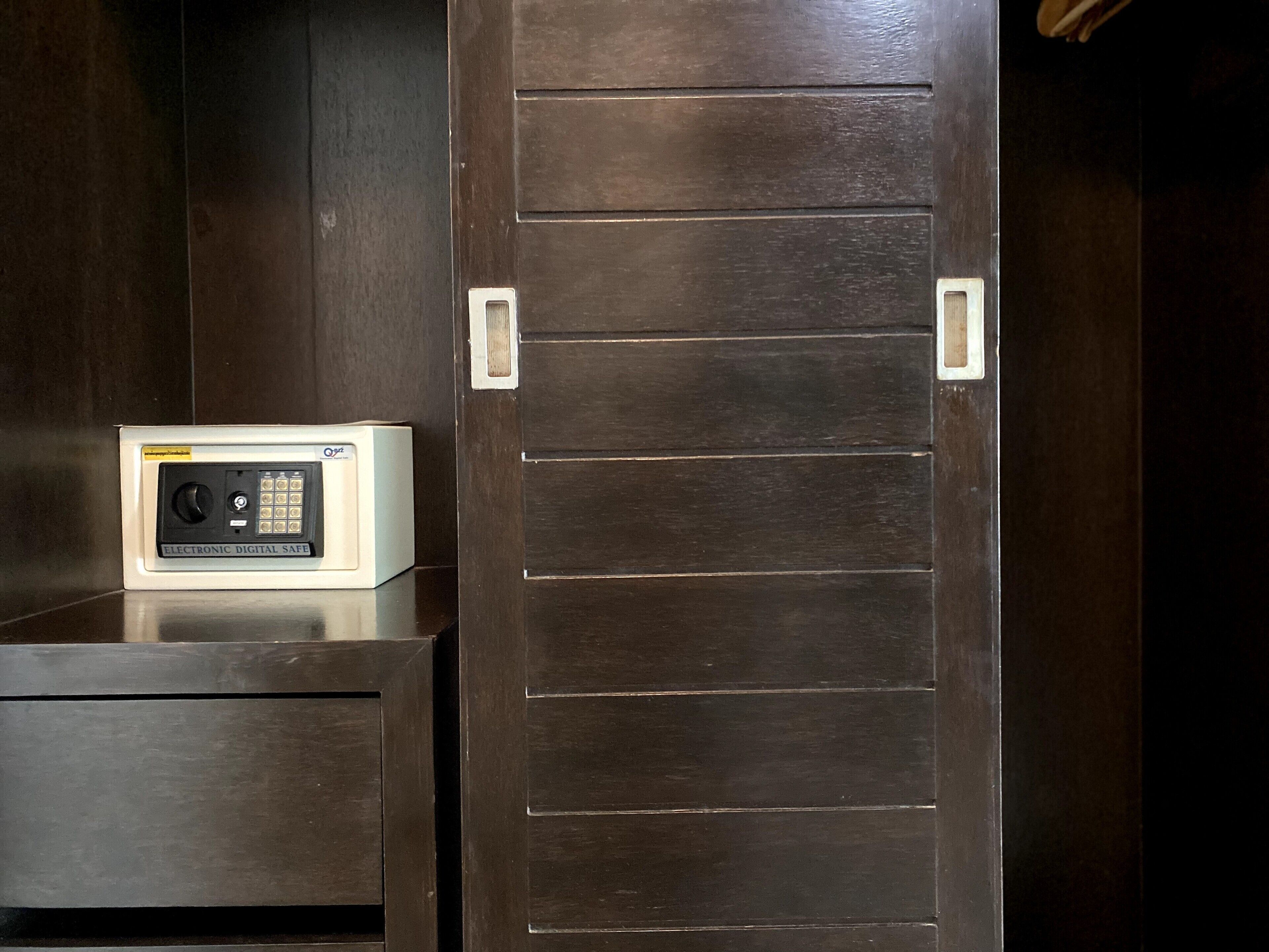 Ein Zimmer mit einer dunklen Holztür, einem weißen elektronischen Safe und einem kleinen Tisch.