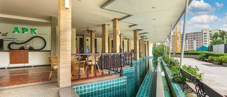 Un espacio exterior cubierto con piscina, asientos y una recepción con letrero 'APK'.