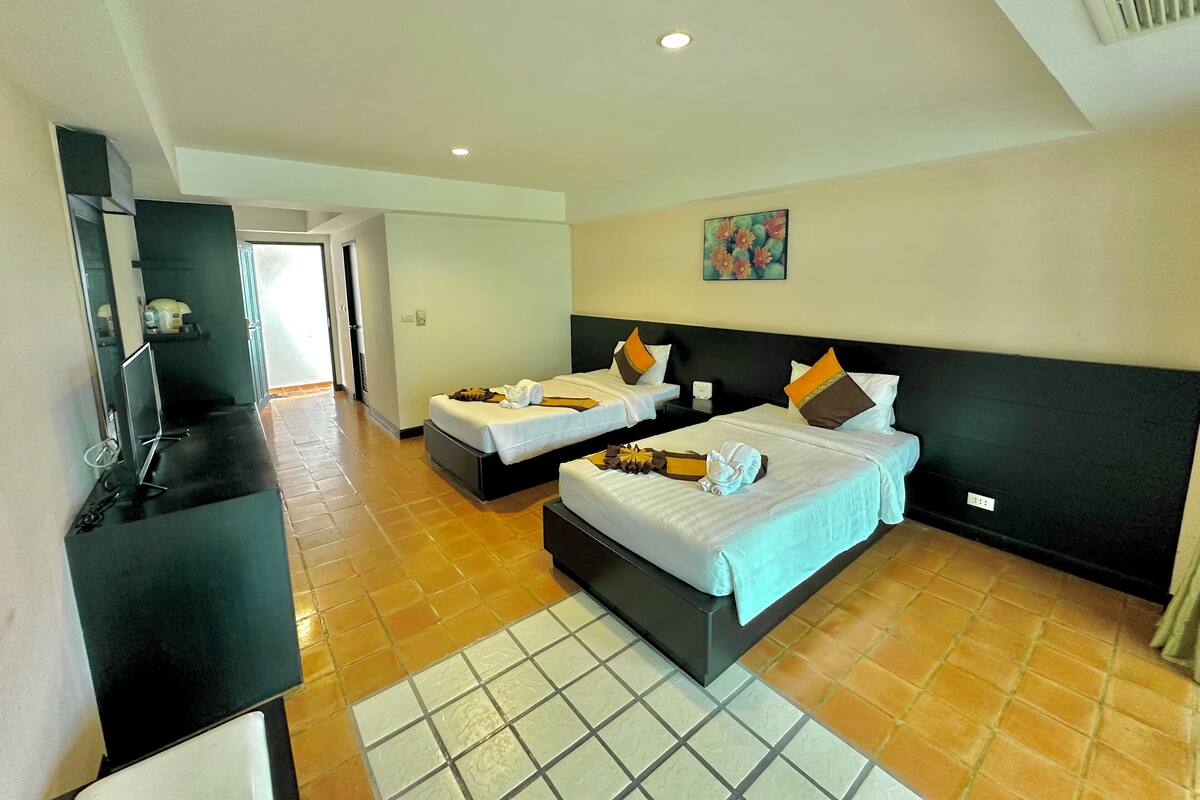 A hotel room with two beds, a TV, and a bathroom visible through an open door.