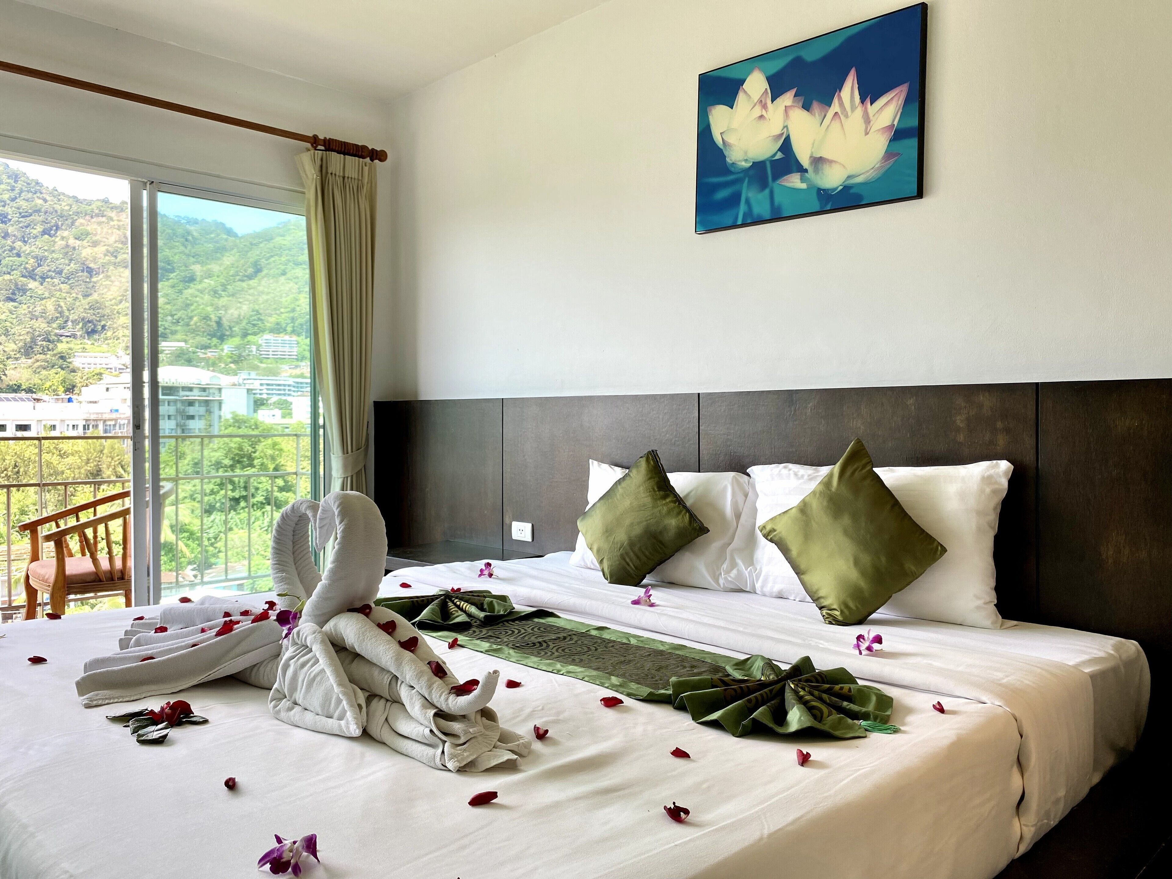 A hotel room with a bed, pillows, a towel, and a painting.