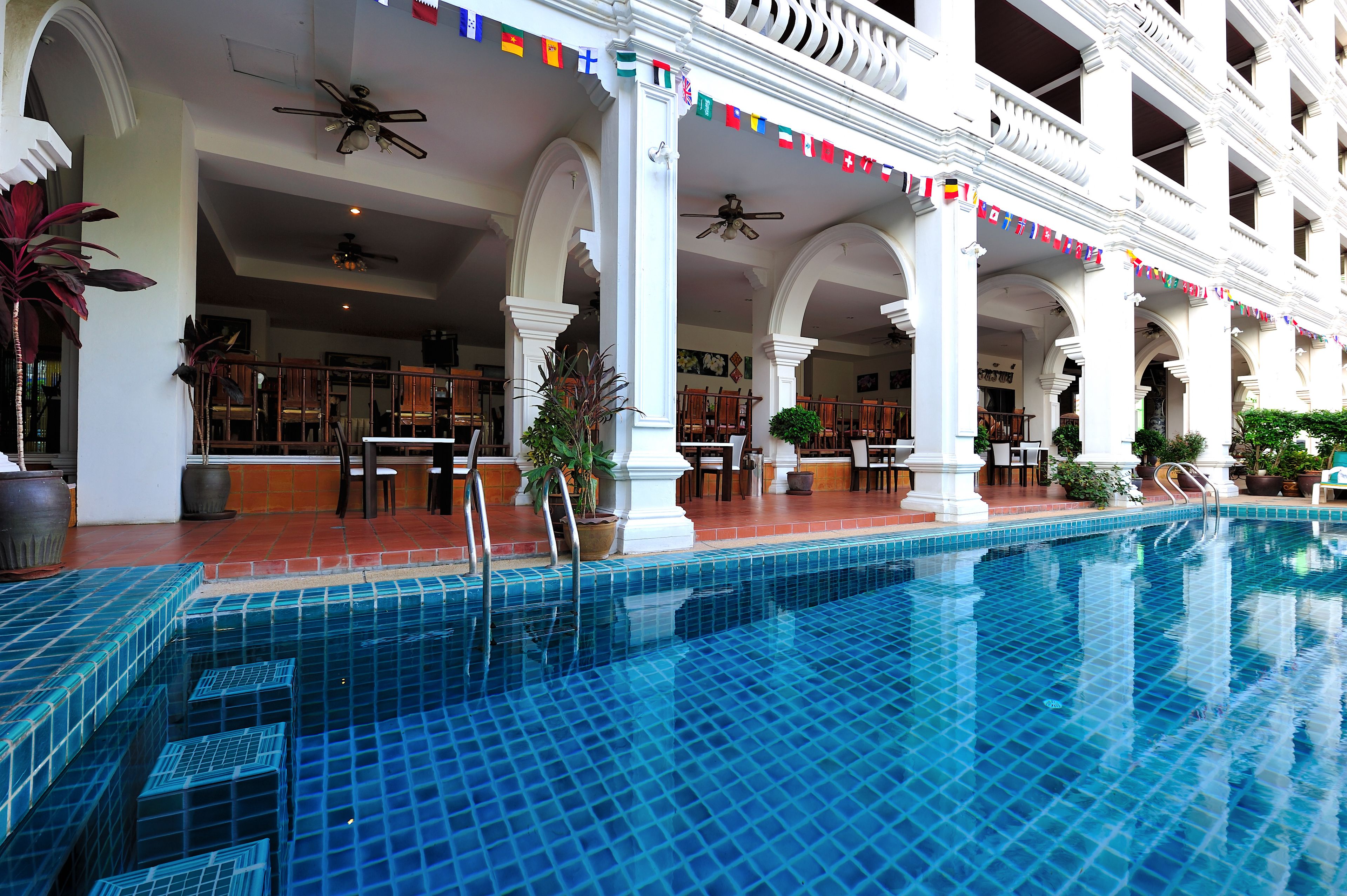 A hotel pool area with multiple seating arrangements and a covered patio.