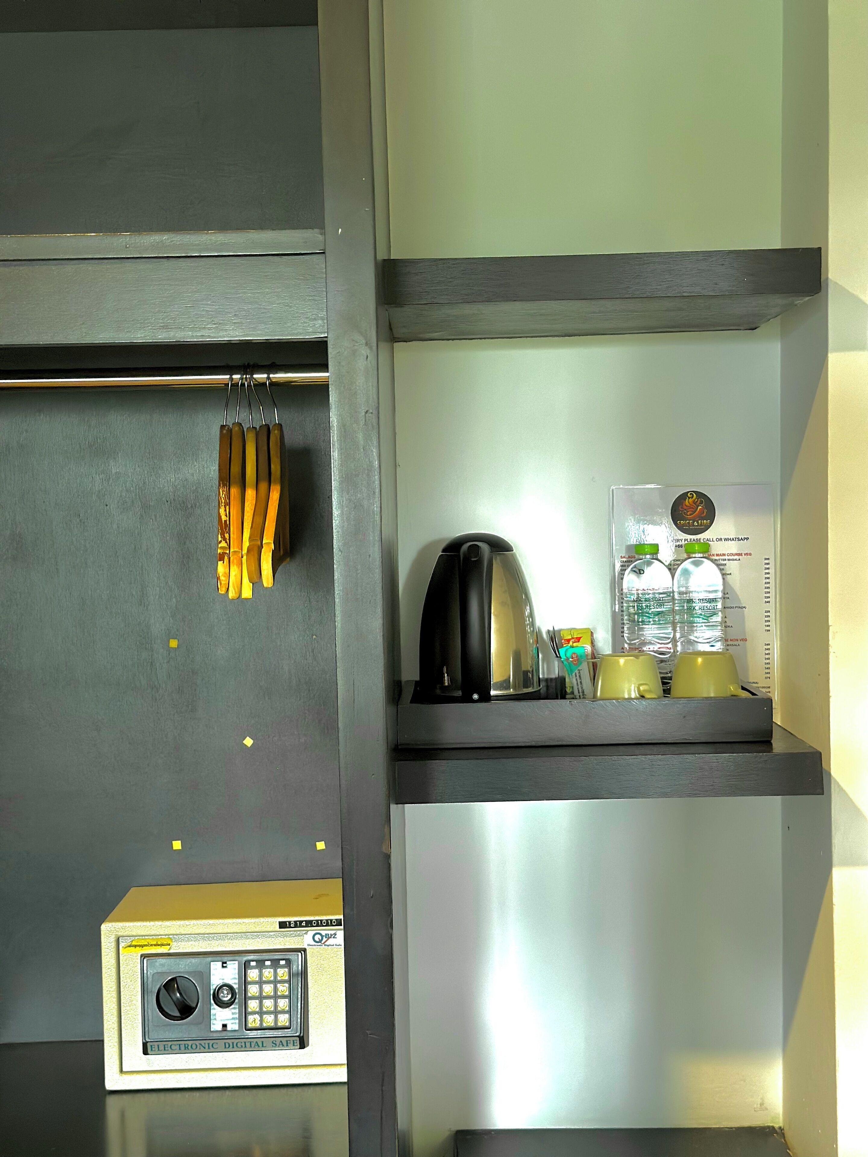 A kitchen area with a coffee machine, a kettle, and a digital safe.