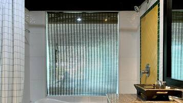 A modern bathroom with a large bathtub, a sink with a granite countertop, and a shower with a glass door.