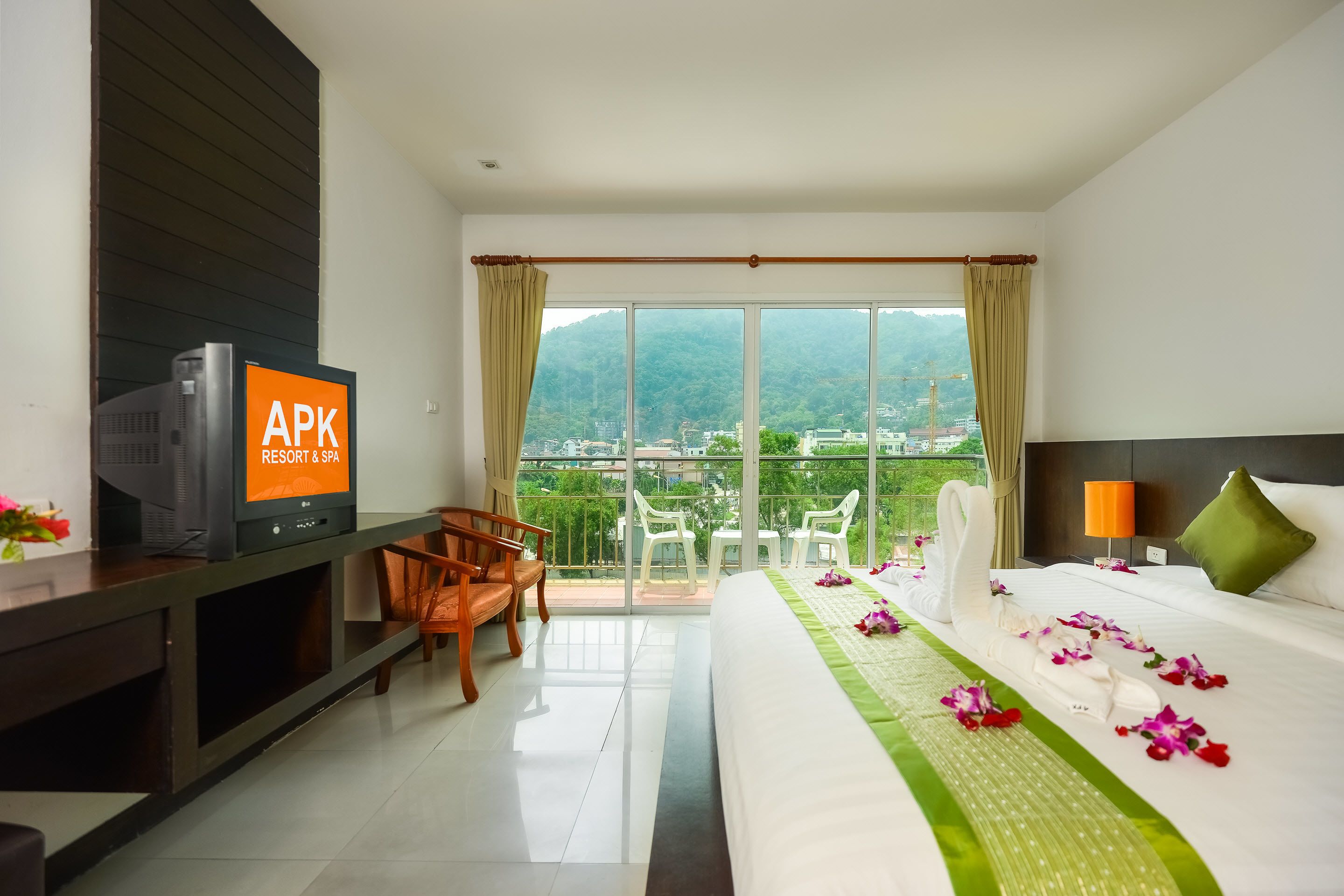 A hotel room with a bed, a TV, a desk, and a view of the city.