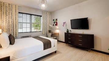 Un dormitorio moderno con cama, televisor, escritorio y cómoda.