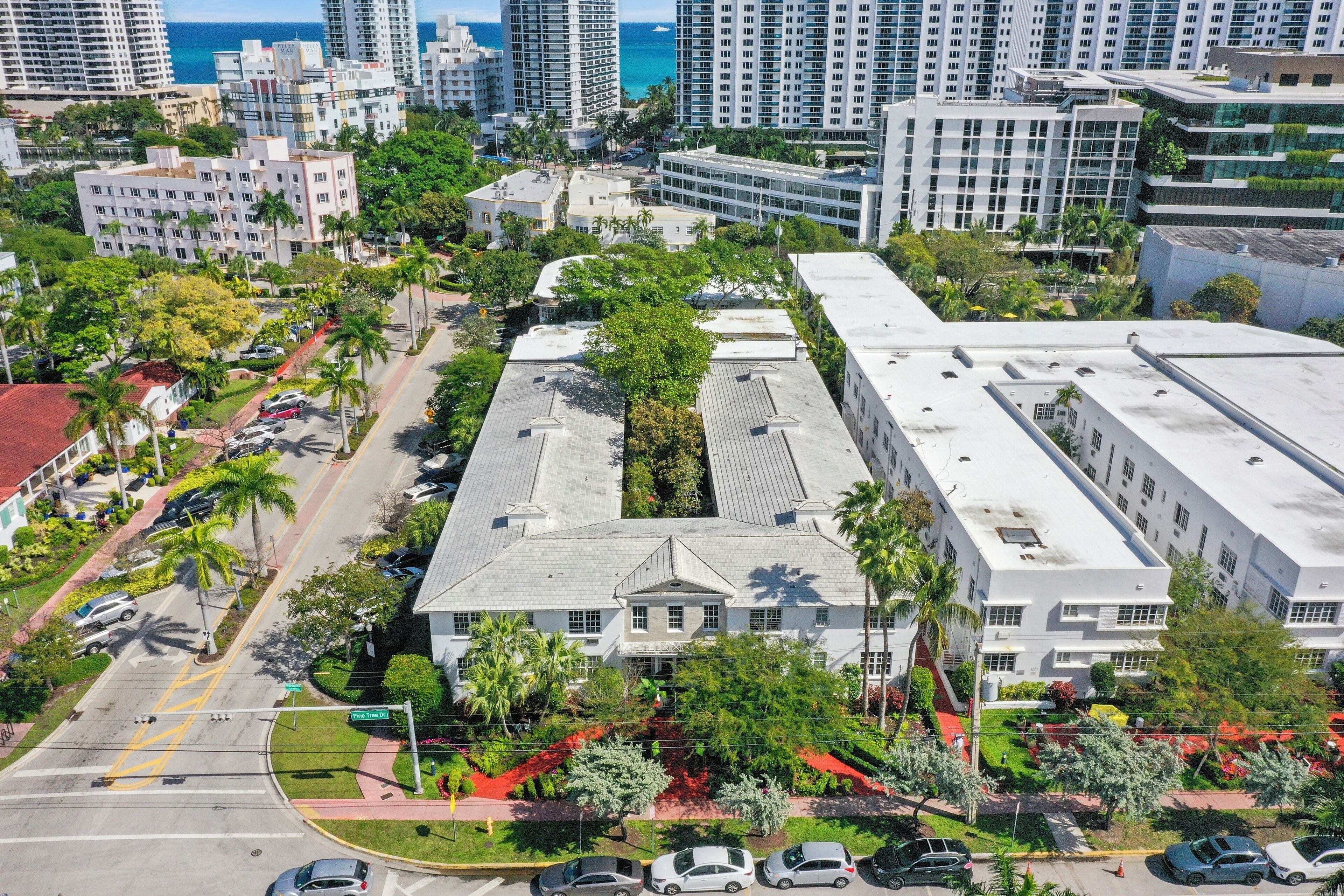 A multi-story hotel with a central courtyard, surrounded by palm trees and a parking lot.