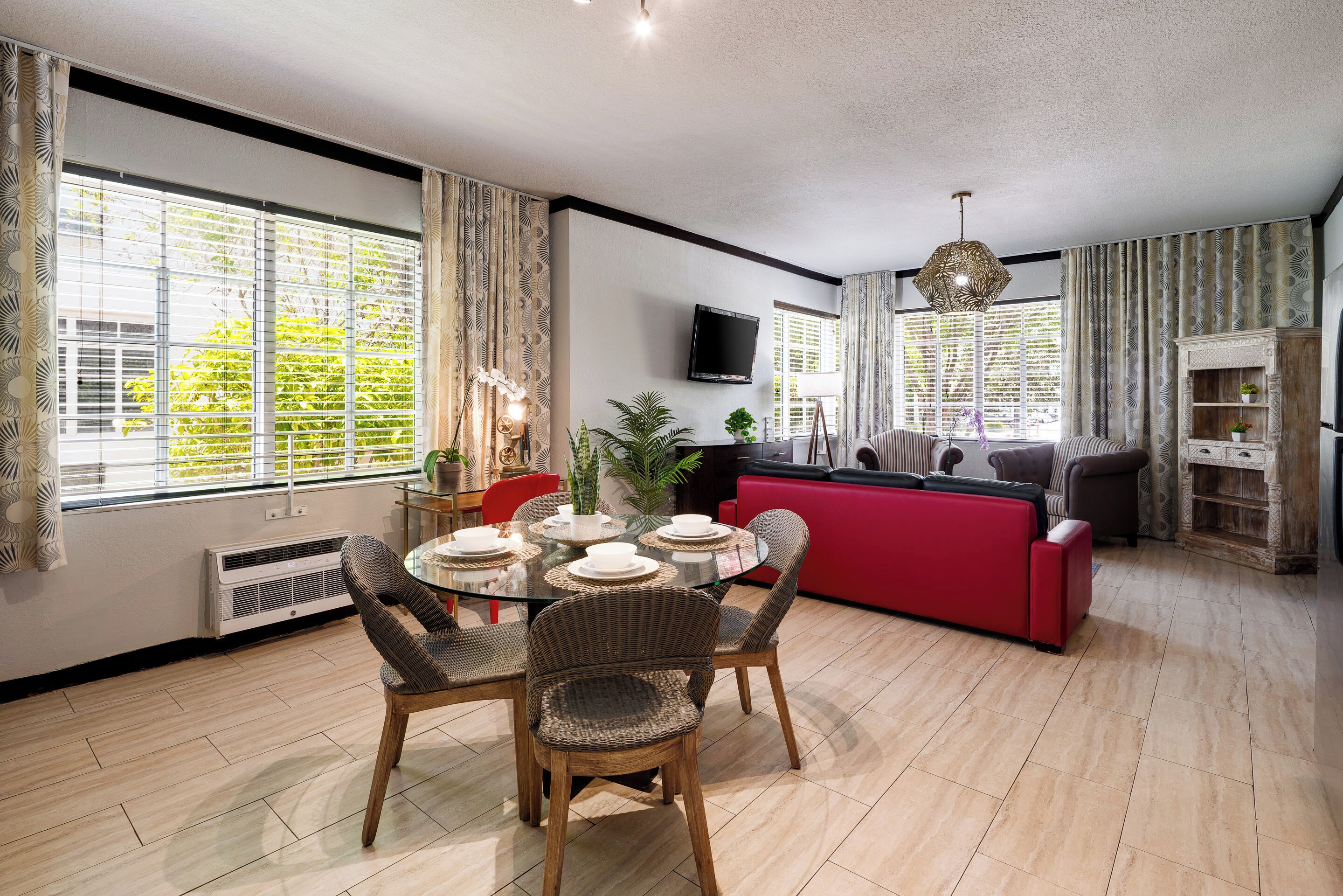 Un salon moderne comprenant un coin repas, un canapé rouge et un téléviseur fixé au mur.