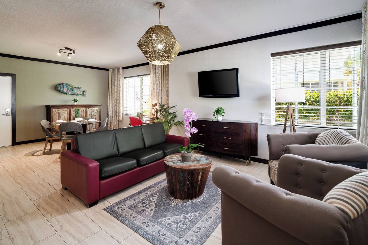 A modern living room with a sofa, armchairs, a coffee table, and a TV.