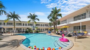 A swimming pool with a poolside area, lounge chairs, and palm trees. - Tradewinds Apartment Hotel (Miami Beach)