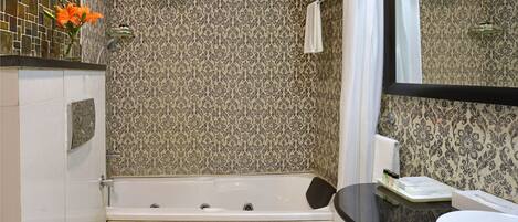 A bathroom with a white bathtub, a toilet, and a sink. There is a mirror above the sink and a showerhead above the bathtub.