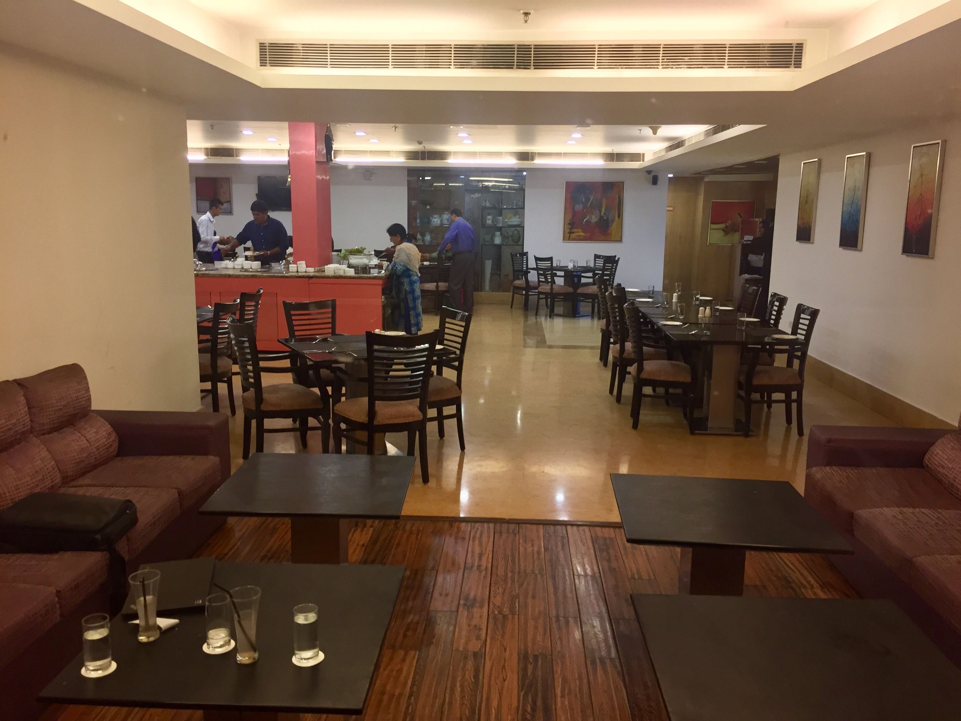 A restaurant with wooden flooring, multiple dining tables and chairs, and a bar area.