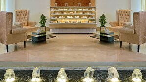 A lobby with two plush armchairs, a display case with pastries, and a water feature.