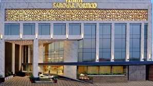 A modern building with a marble facade, large windows, and a sign reading "Taurus Sarovar Portico."