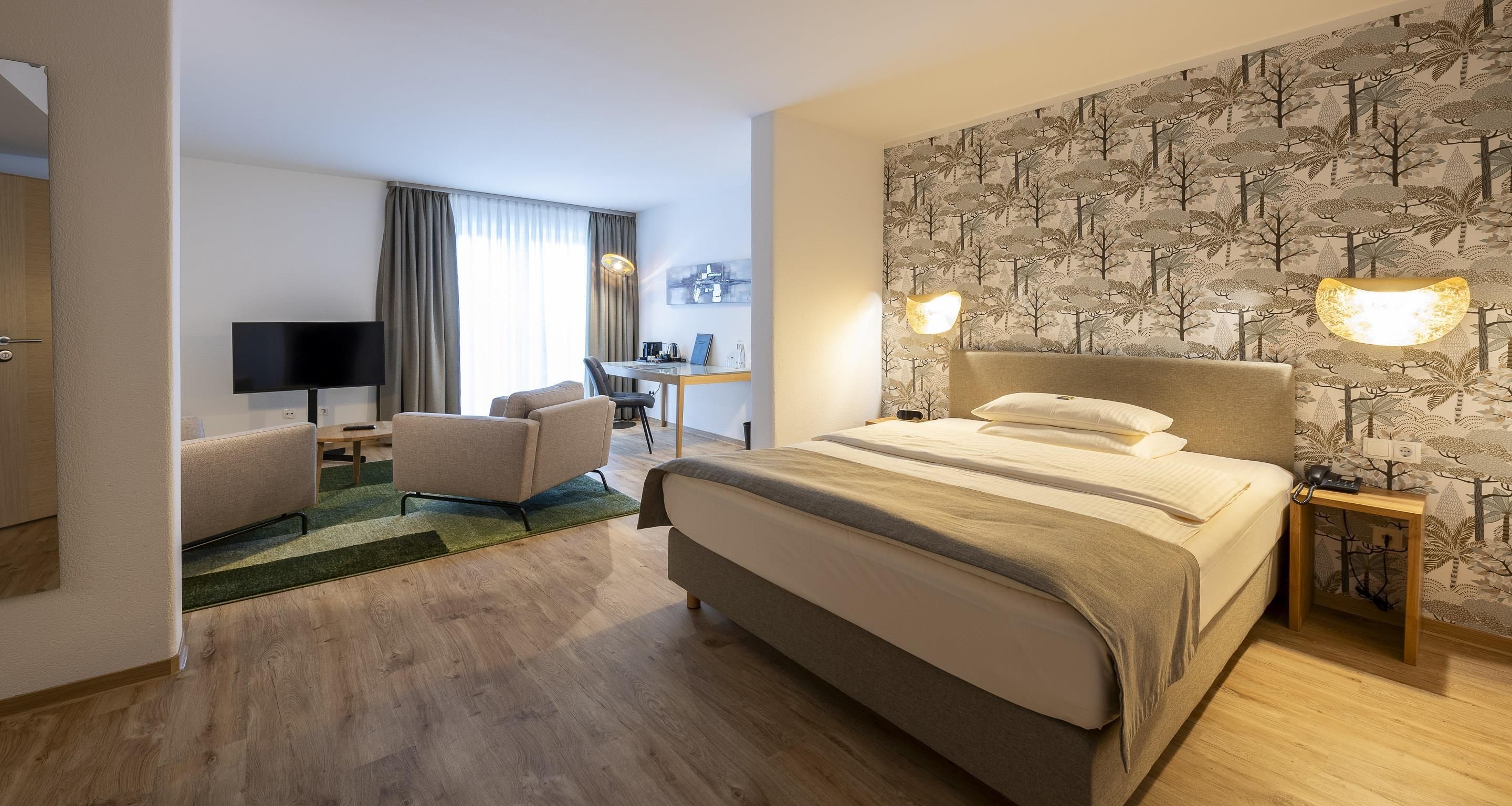 A hotel room with a bed, a desk, a chair, and a television.