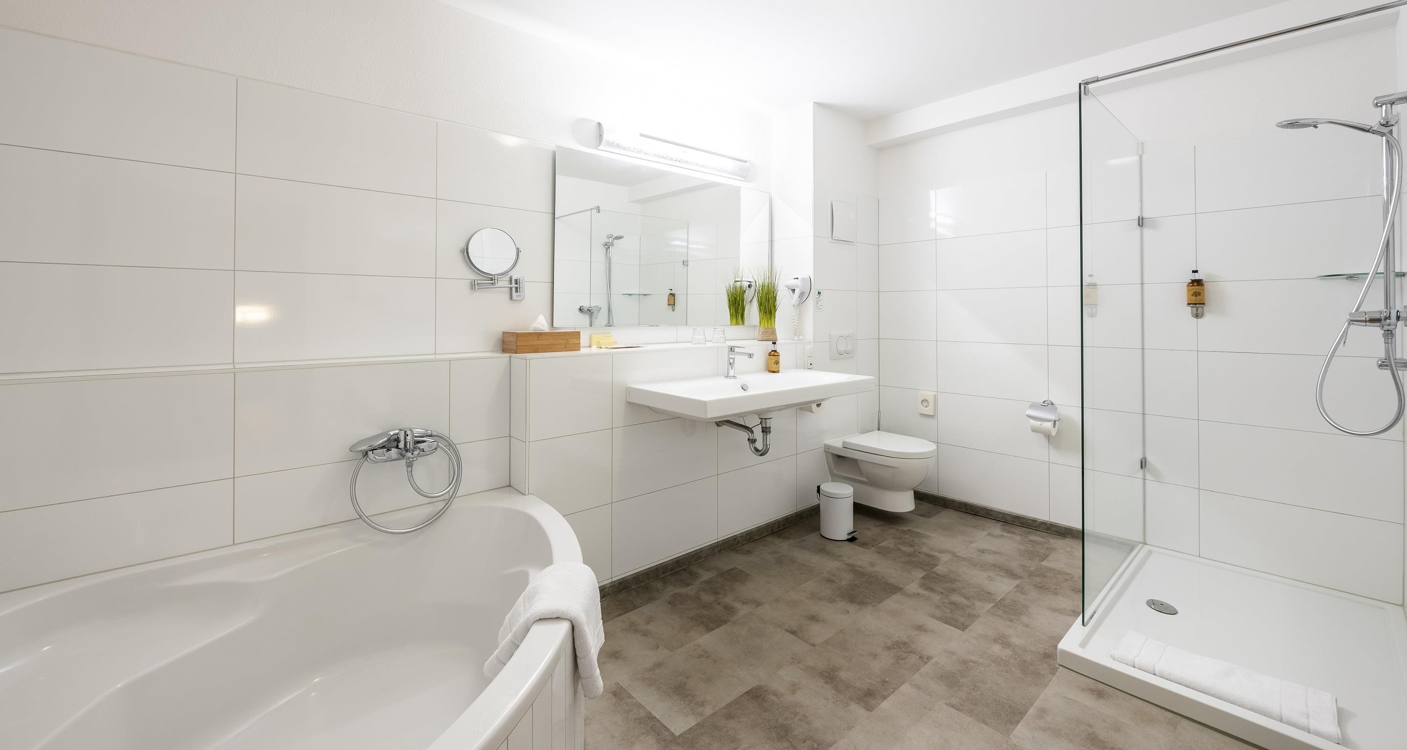 A modern bathroom with a bathtub, toilet, and glass-enclosed shower area.