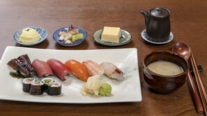 A variety of sushi on a rectangular plate, a small bowl of soup, a teapot, and chopsticks on a wooden table. - Best Western Plus iO Hotel (Schwalbach am Taunus)