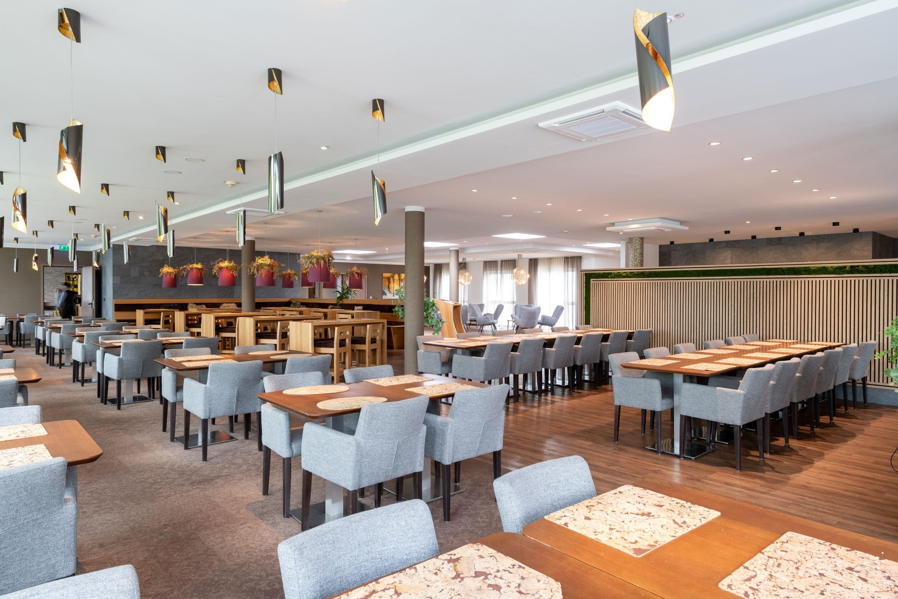 Eine moderne Hotelhalle mit mehreren Sitzbereichen, einem Empfangstresen und einer grünen Wand.