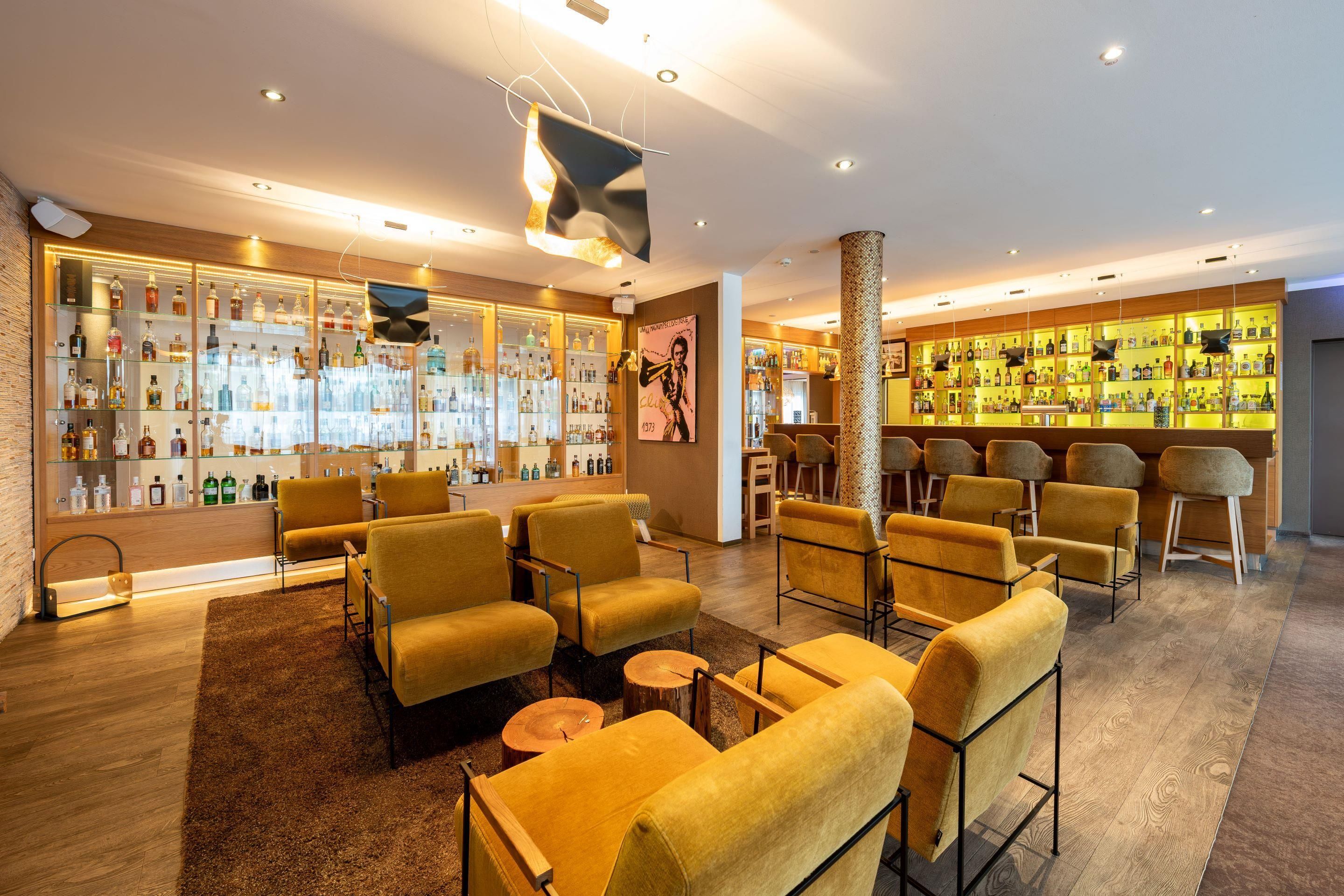 A bar area with multiple seating options, a well-stocked liquor display, and a modern interior design.
