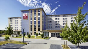 A multi-story hotel with a prominent Best Western Plus sign, a paved courtyard, and surrounding greenery. - Best Western Plus iO Hotel (Schwalbach am Taunus)