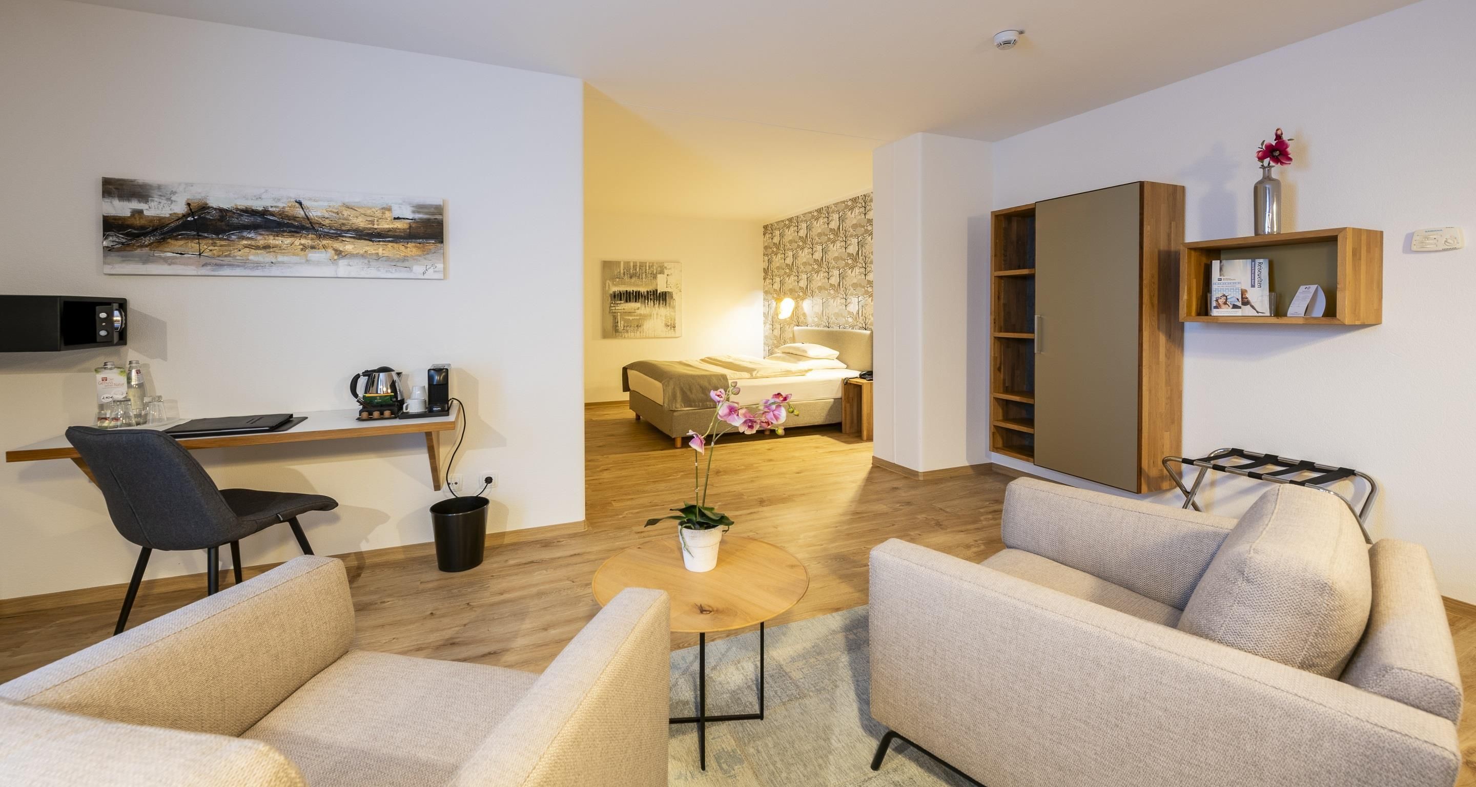 A modern living room with a sofa, armchair, coffee table, and a TV on a stand.