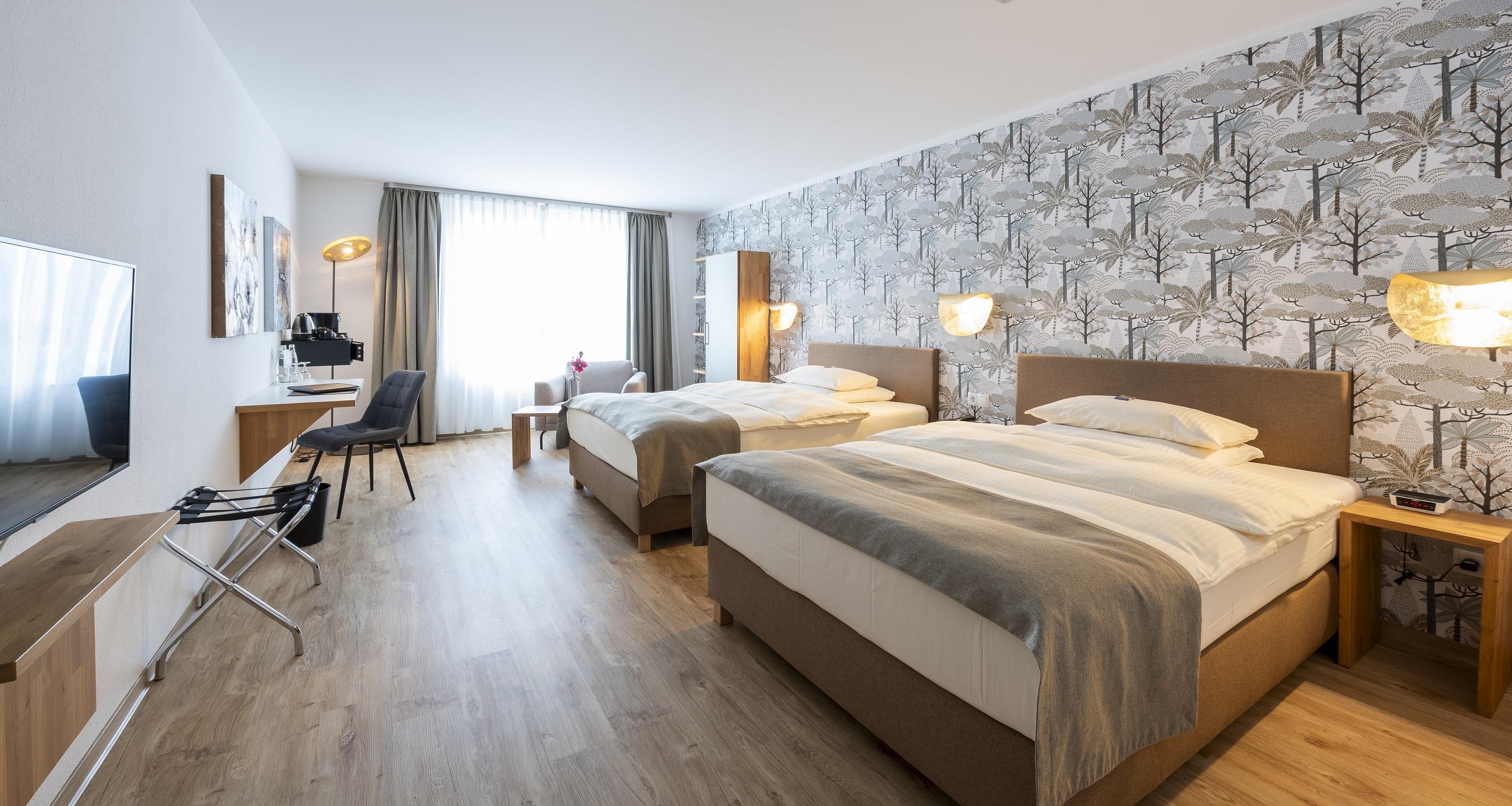 Una habitación de hotel con una cama, mesitas de noche, un escritorio, una silla y un televisor.