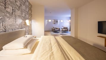 Una habitación de hotel con cama, televisión y zona de estar con mesa y sillas.
